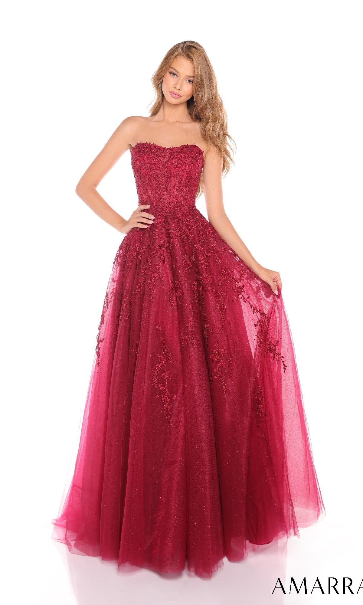 A young woman in the Amarra 88258 long prom dress, a red strapless ball gown with lace and tulle details, stands against a white background.